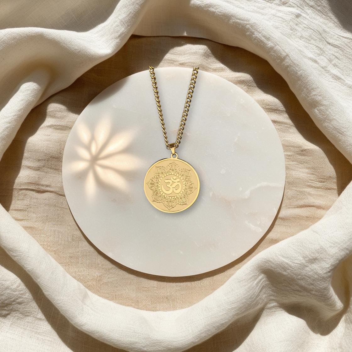 Collier Talisman Lotus & Om en acier inoxydable doré, posé à plat, dans l'univers spirituel et minimaliste d'Âme de Lune. Parfait pour la méditation et l'ancrage.