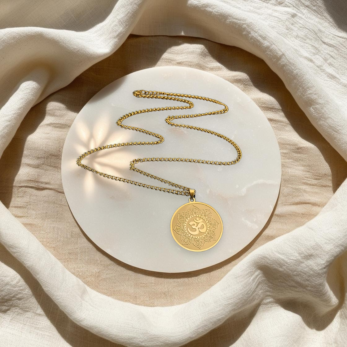 Collier Talisman Lotus & Om en acier inoxydable doré, posé à plat, dans l'univers spirituel et minimaliste d'Âme de Lune. Parfait pour la méditation et l'ancrage et la pleine conscience.