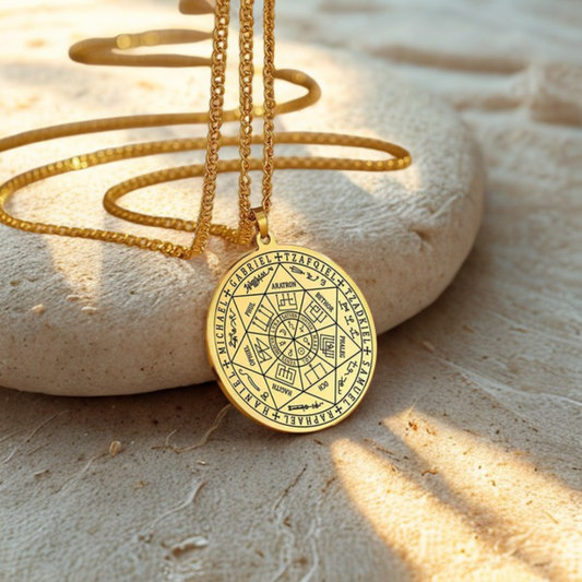 Talisman des 7 Archanges en acier doré, collier de protection énergétique avec gravures sacrées, présenté sur un fond sable lumineux et naturel.